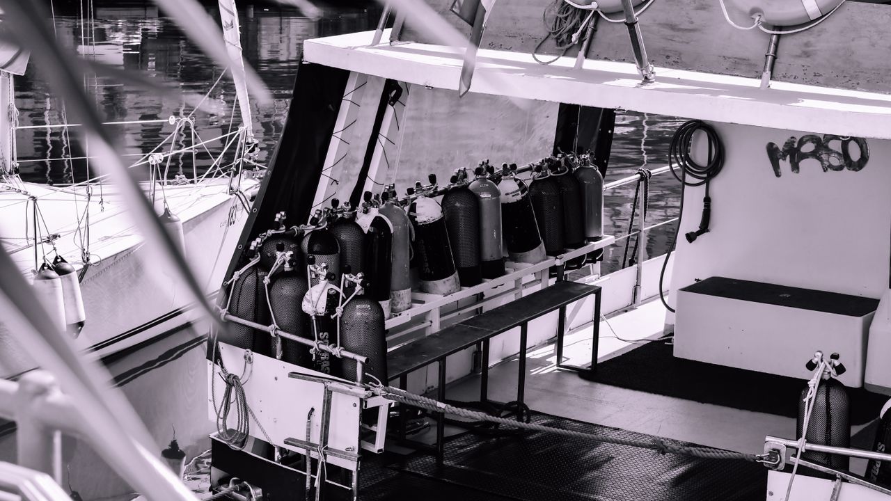 Black and white photo of scuba tanks lined up on a dive boat deck