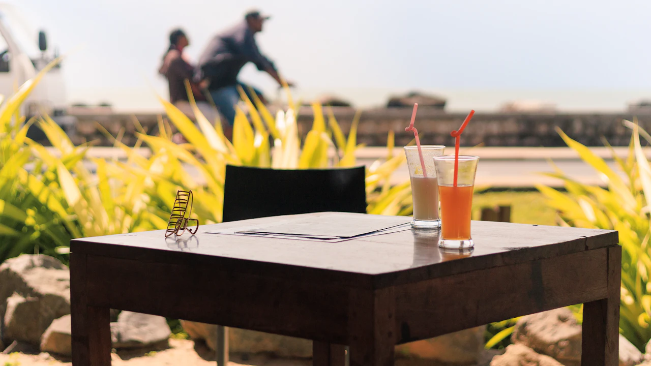 Two cold drinks on a wooden table by the beach