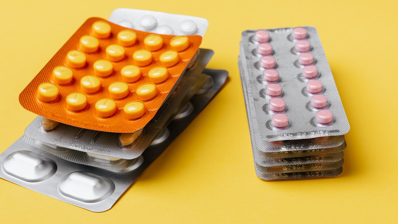 Blister packs of colorful tablets on a yellow background