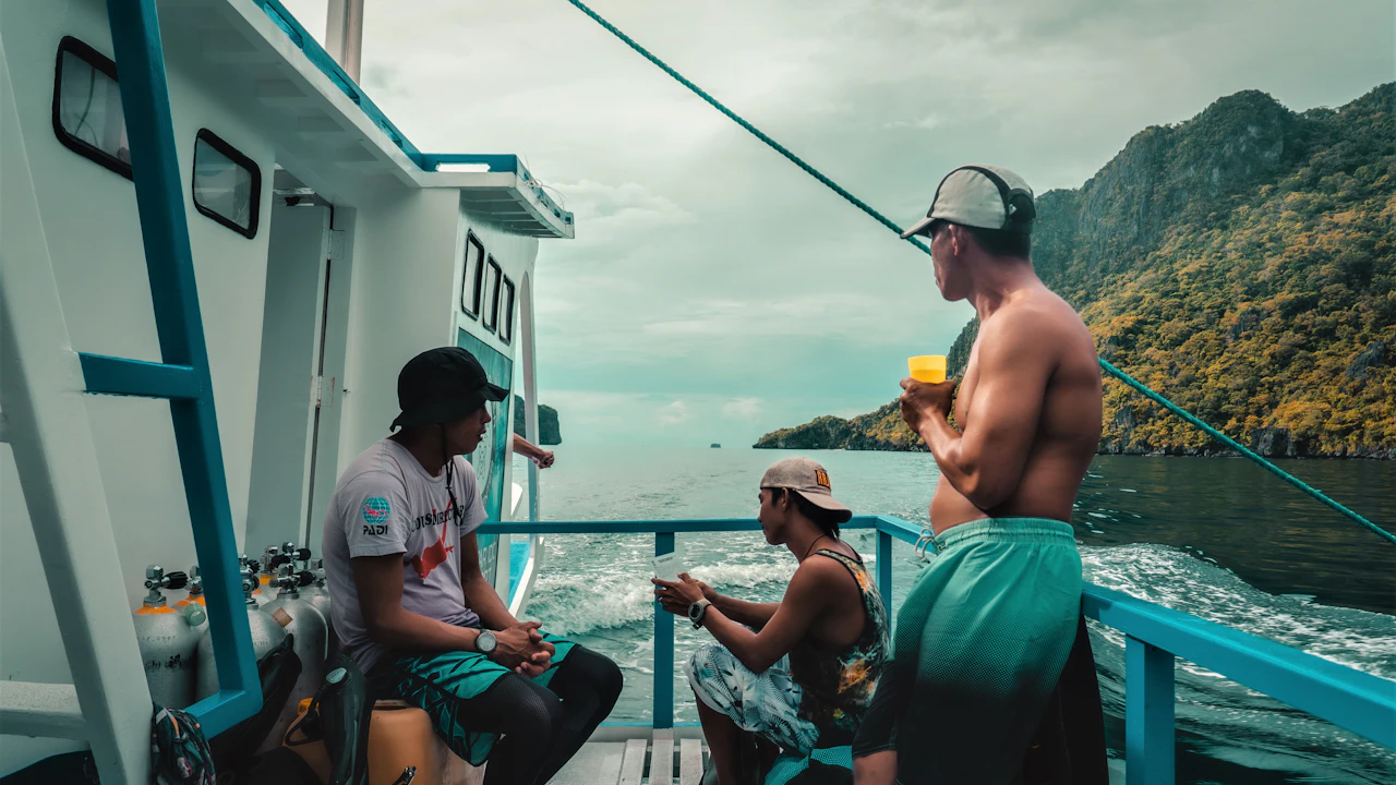 Group relaxing on the deck of a dive boat near rocky cliffs