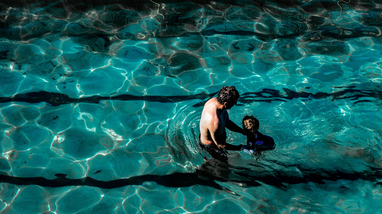 Adult helping a child in a swimming pool