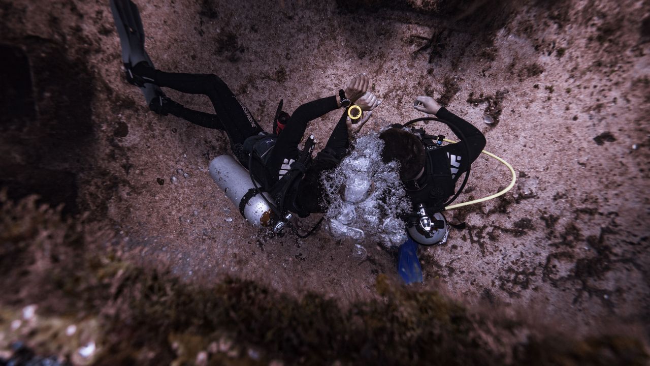 Two scuba divers kneeling on the seabed