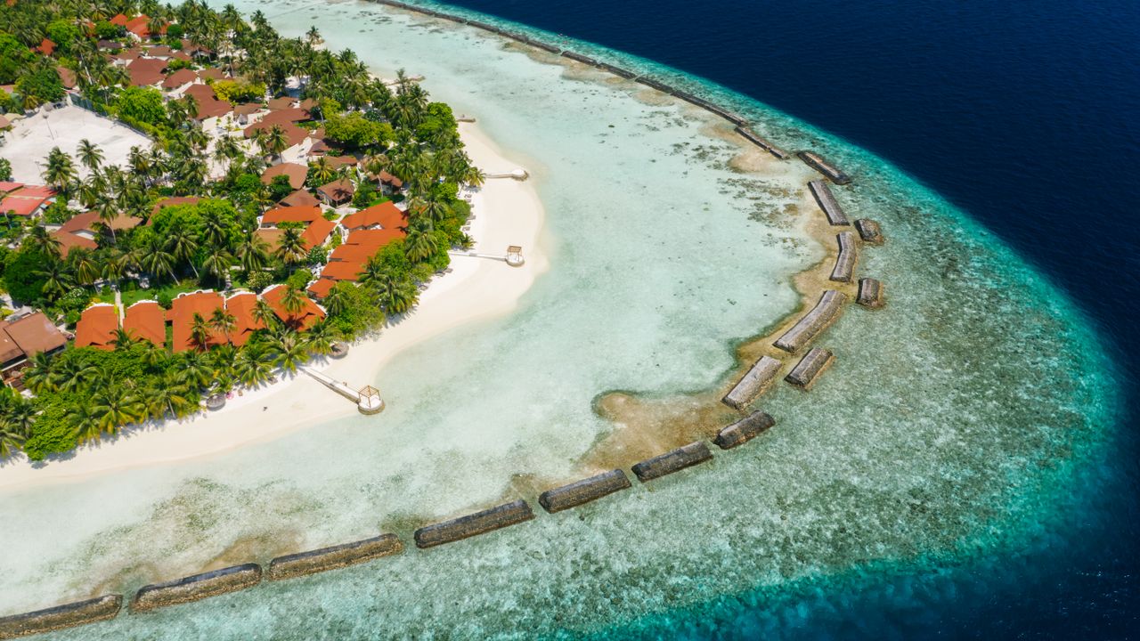 Aerial view of a reef-fringed island with a turquoise lagoon