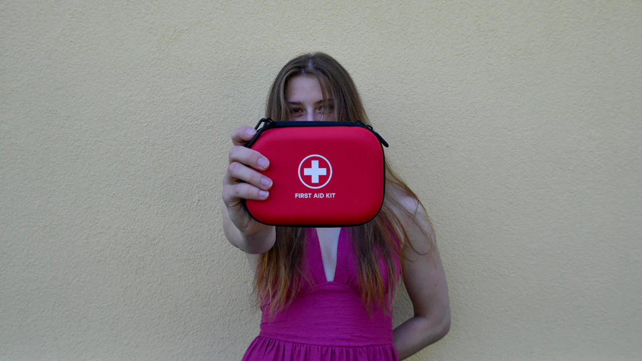 Woman holding up a red first aid pouch