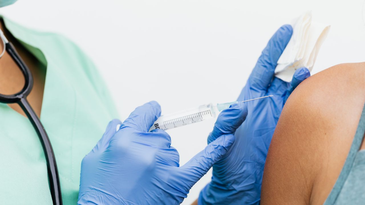 Nurse giving a vaccine injection in a traveler's upper arm