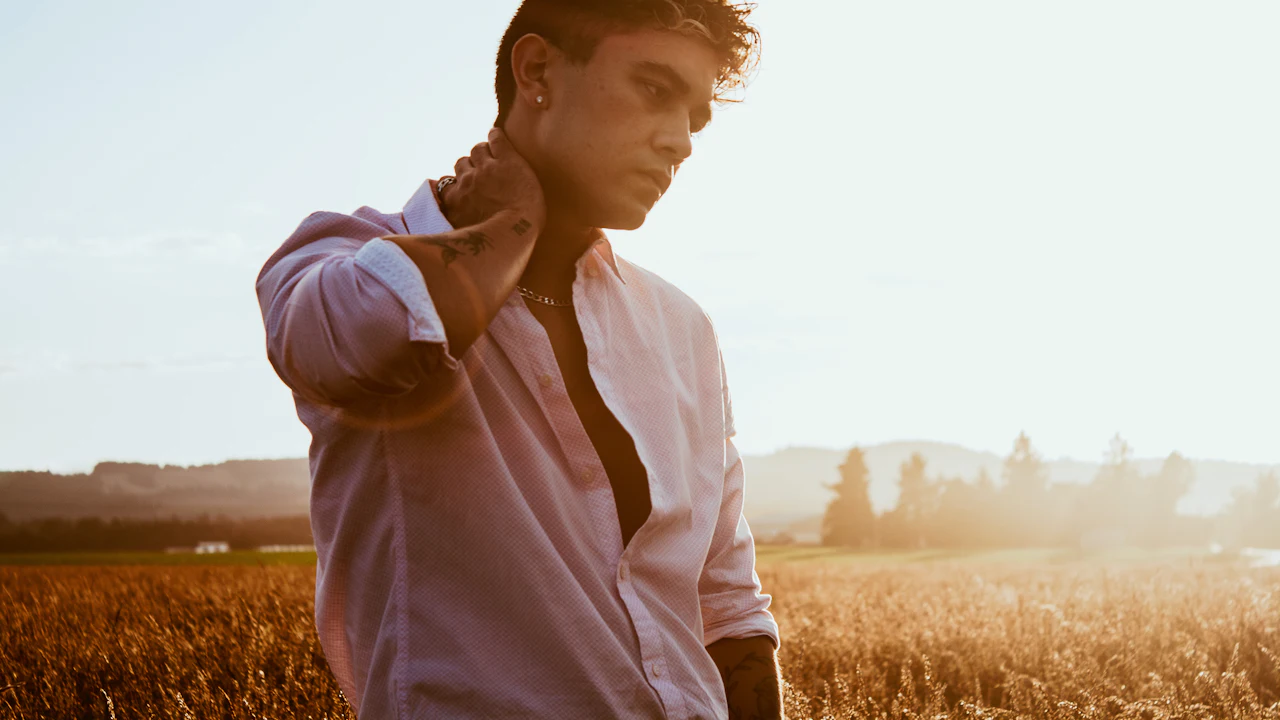 Man holding his neck and shoulder in a sunny field