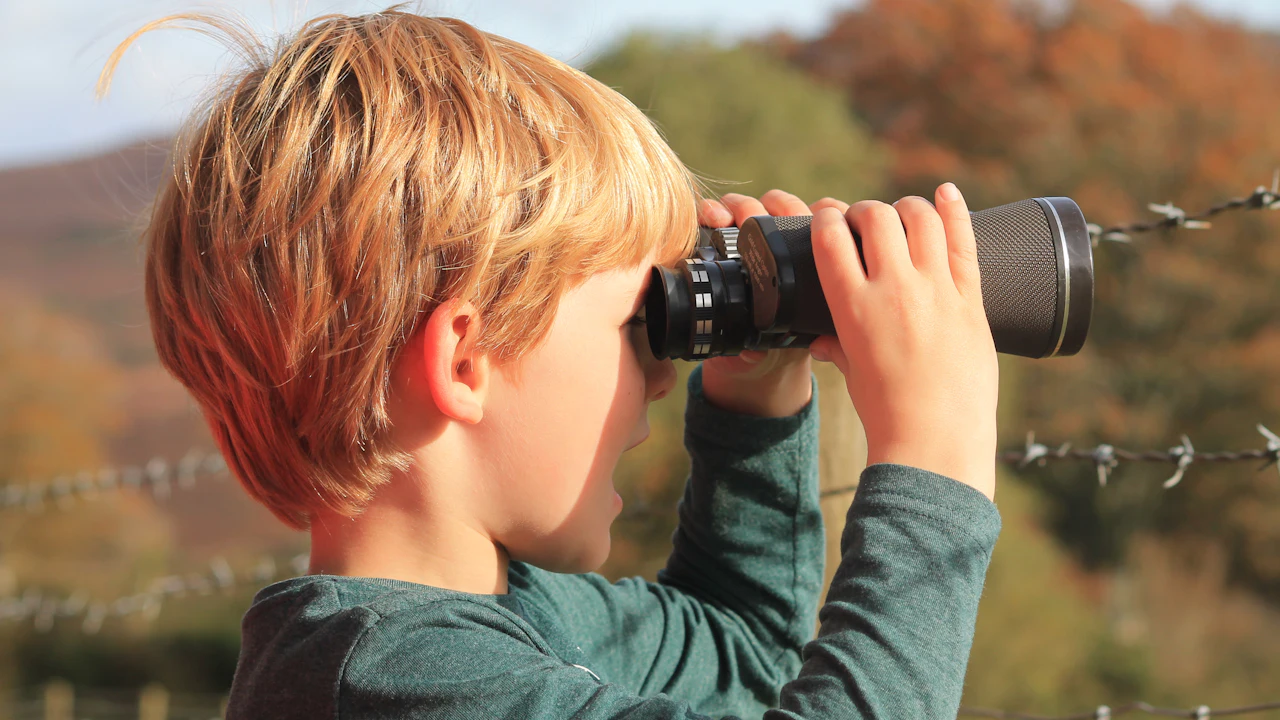 Child looking through binoculars outdoors