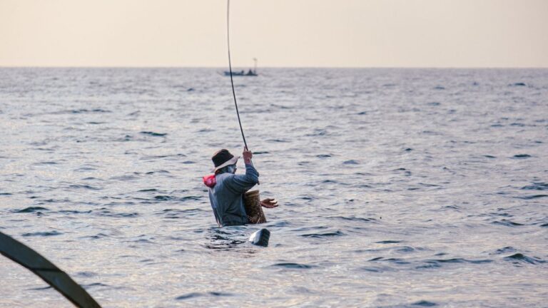 Angler standing in the sea with a bent fishing rod