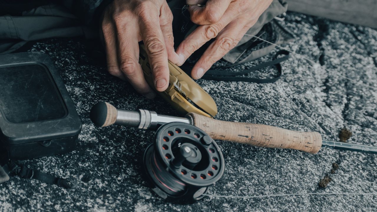 Hands assembling a fly reel and rod