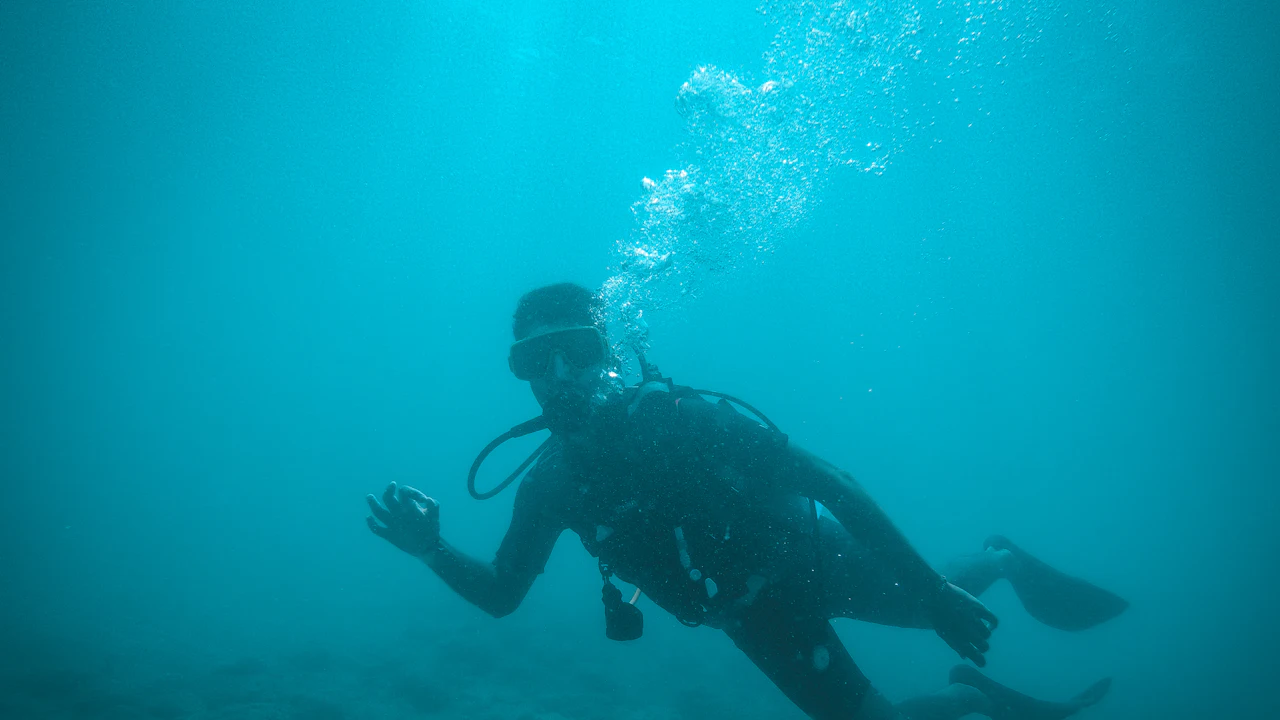 Scuba diver hovering in blue water and looking around for a buddy