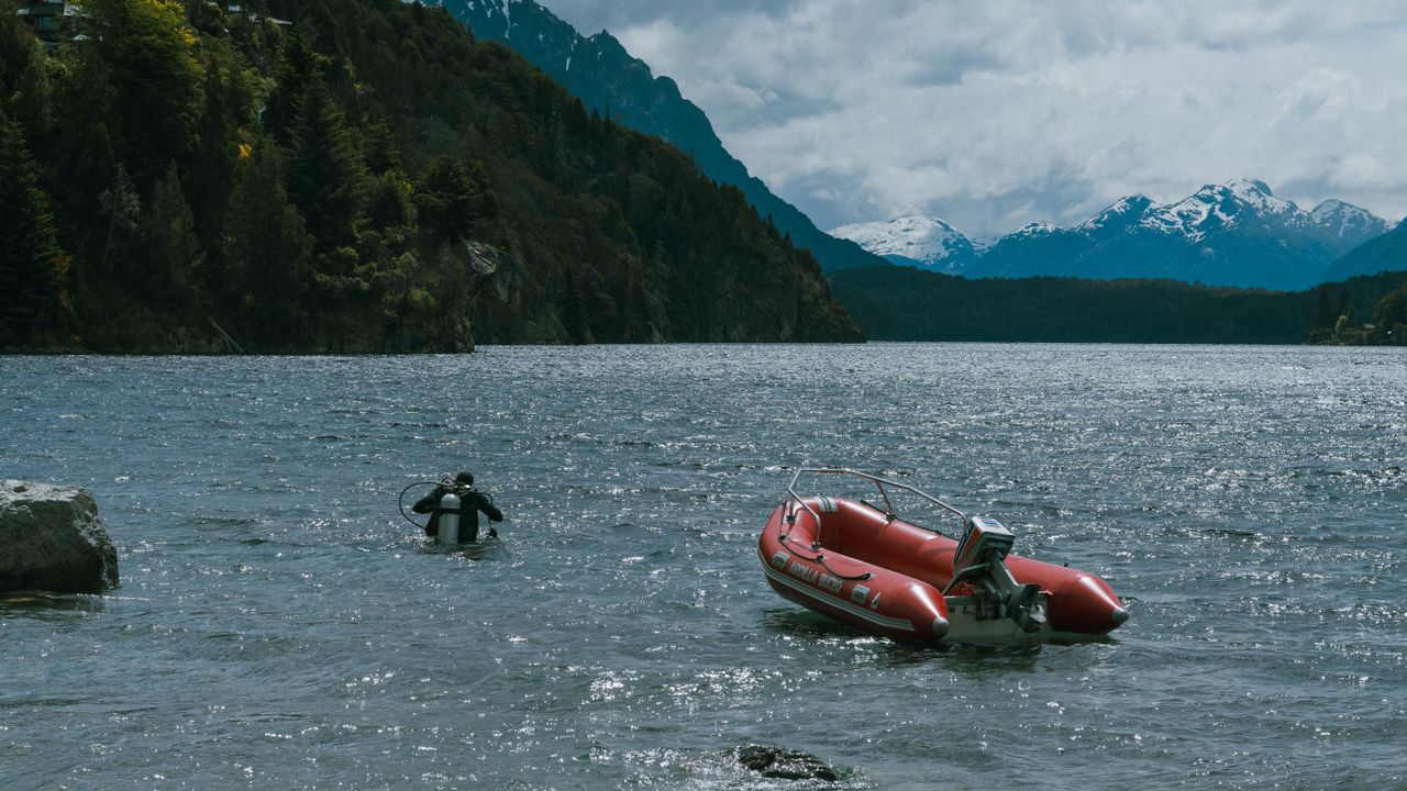 Diver at the surface near a red inflatable boat