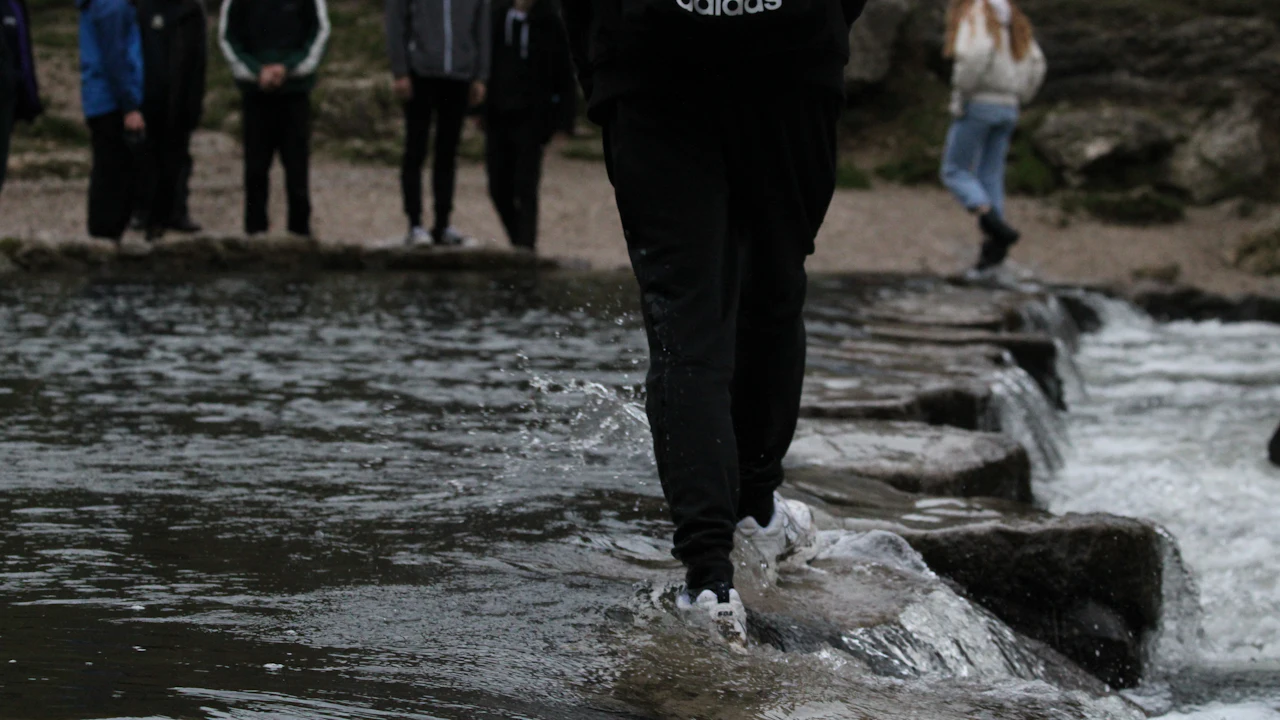 People crossing a shallow stream on stepping stones