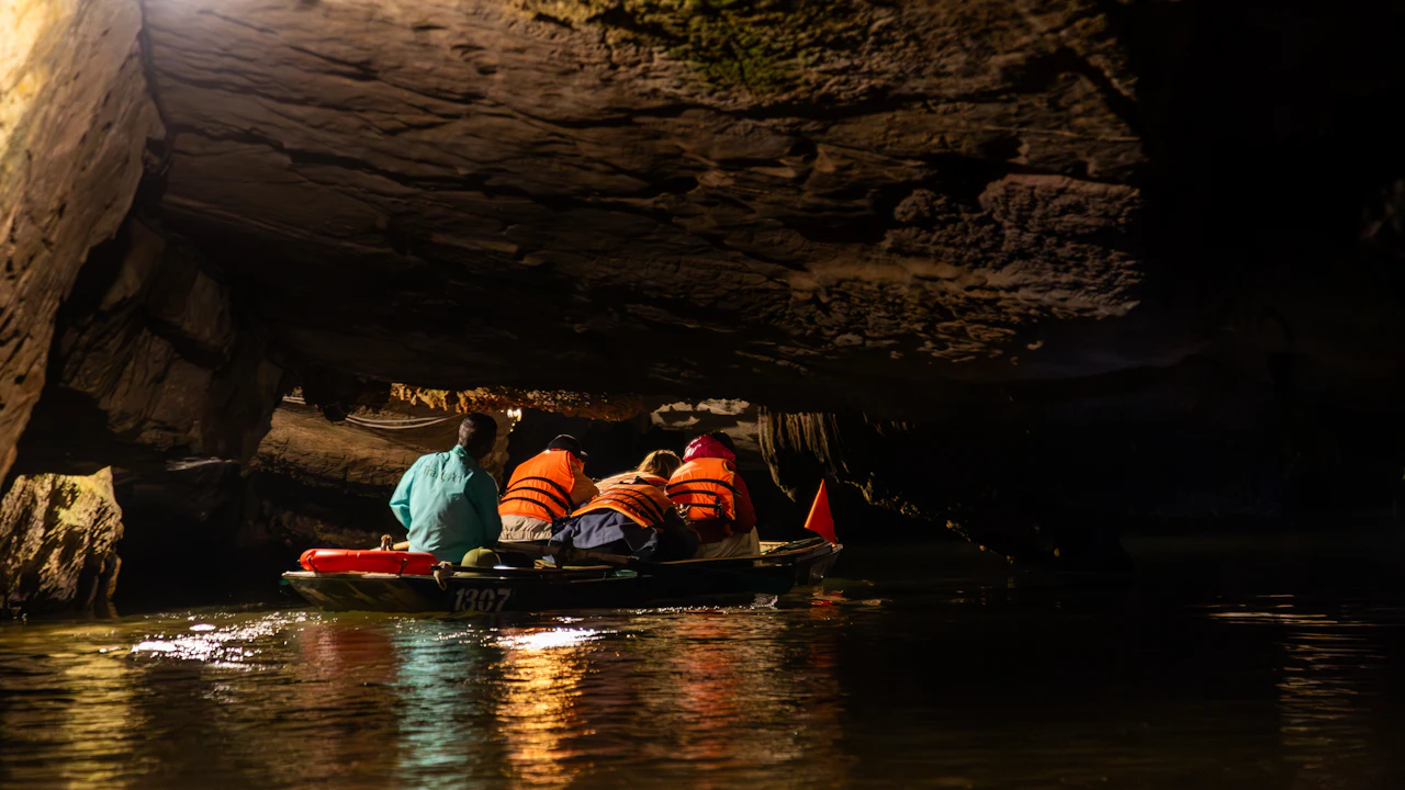 People in a small raft floating through a dark cave