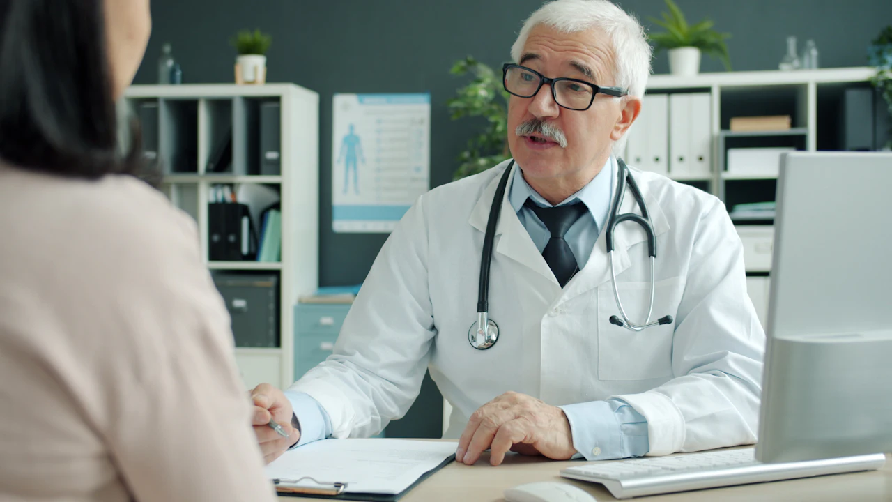Doctor talking with a patient across a desk in a bright medical office