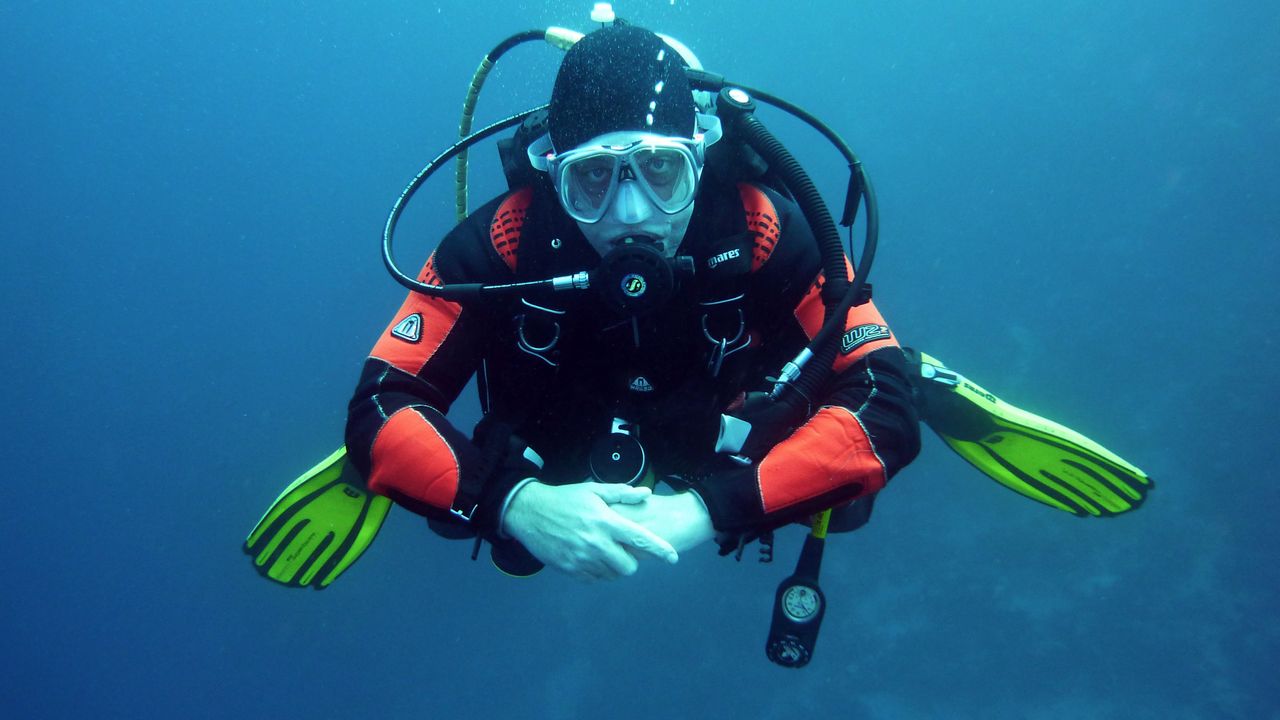 Scuba diver in a mask and regulator hovering in blue water