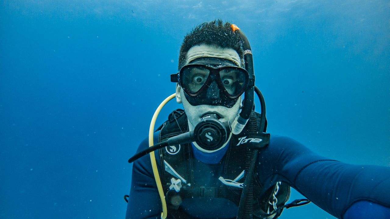 Scuba diver in a mask and regulator in open blue water