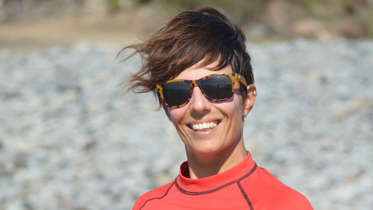 Smiling woman in sunglasses and a red rash guard