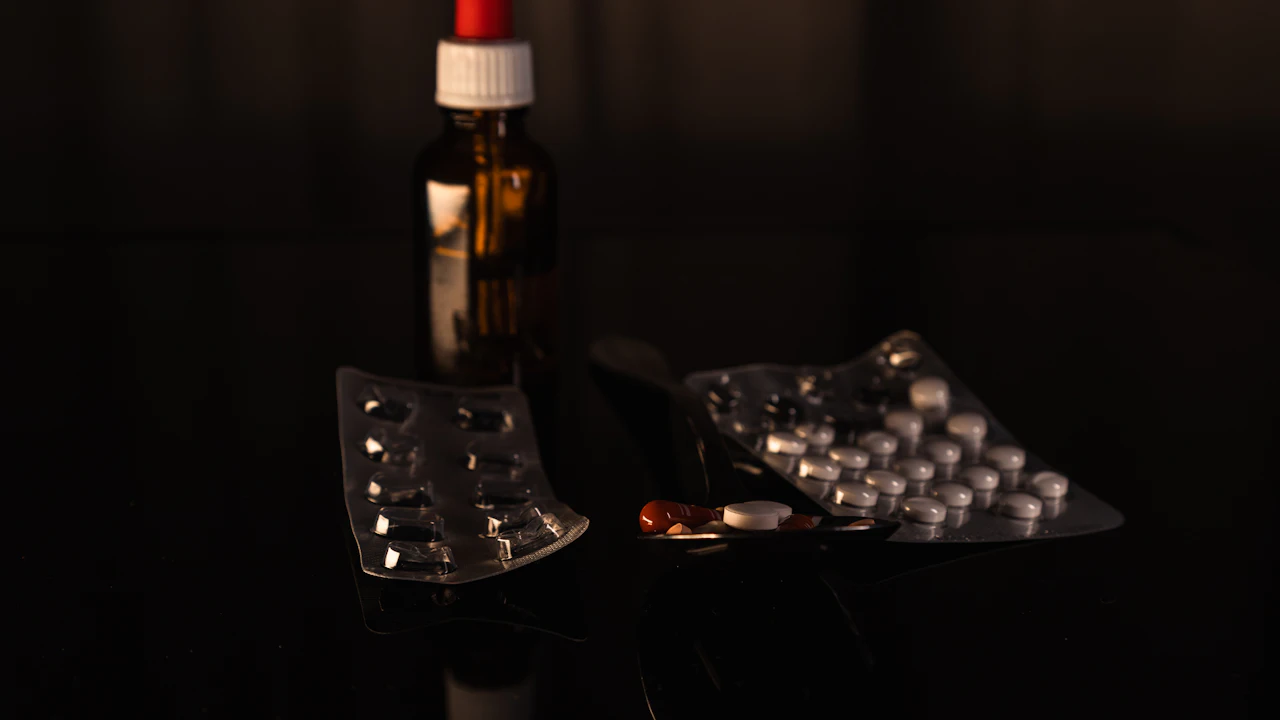 Medicine bottle and blister packs of tablets on a dark table