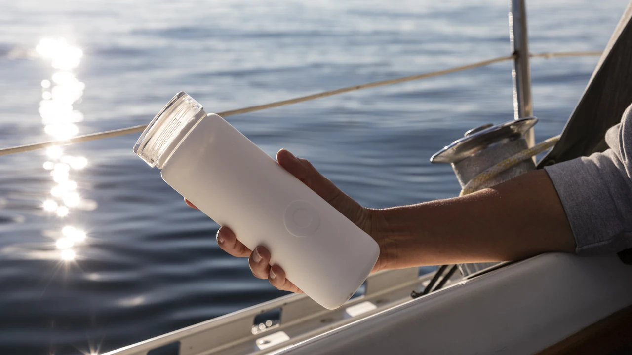 Person drinking from a water bottle on a boat on a sunny day