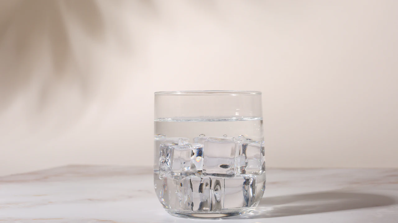 Glass of water with ice on a white table