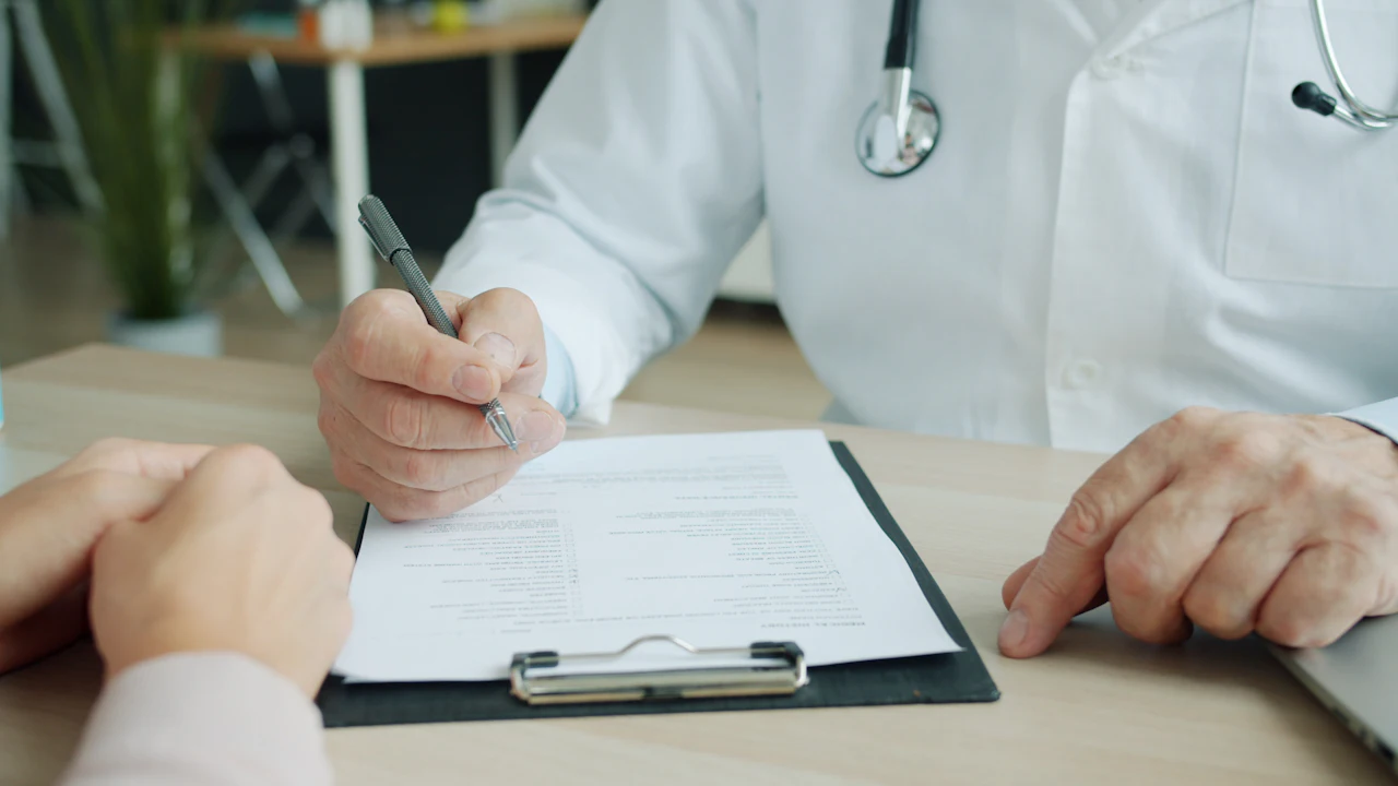Doctor talking with a patient across a desk in a bright clinic office