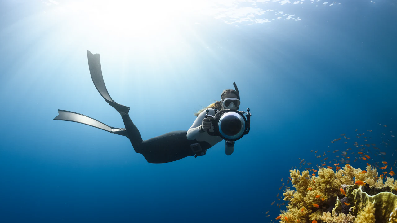 Free diver with an underwater camera swimming above a reef