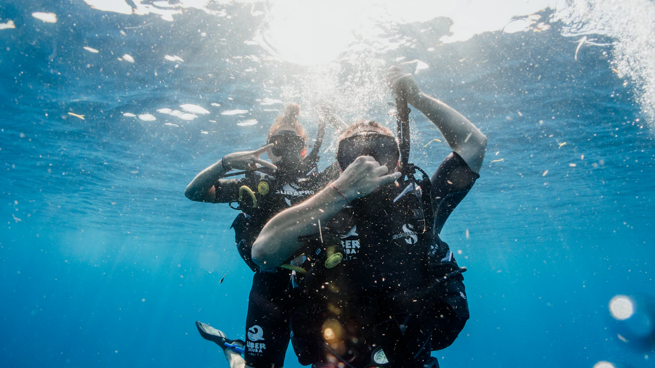 Two scuba divers descending together through sunlit blue water