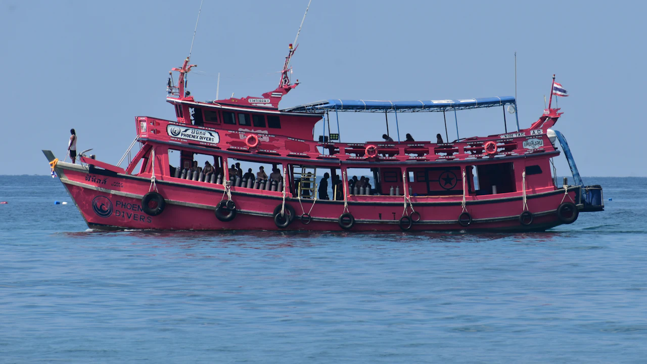 Red and white dive boat with passengers at anchor on a calm sea