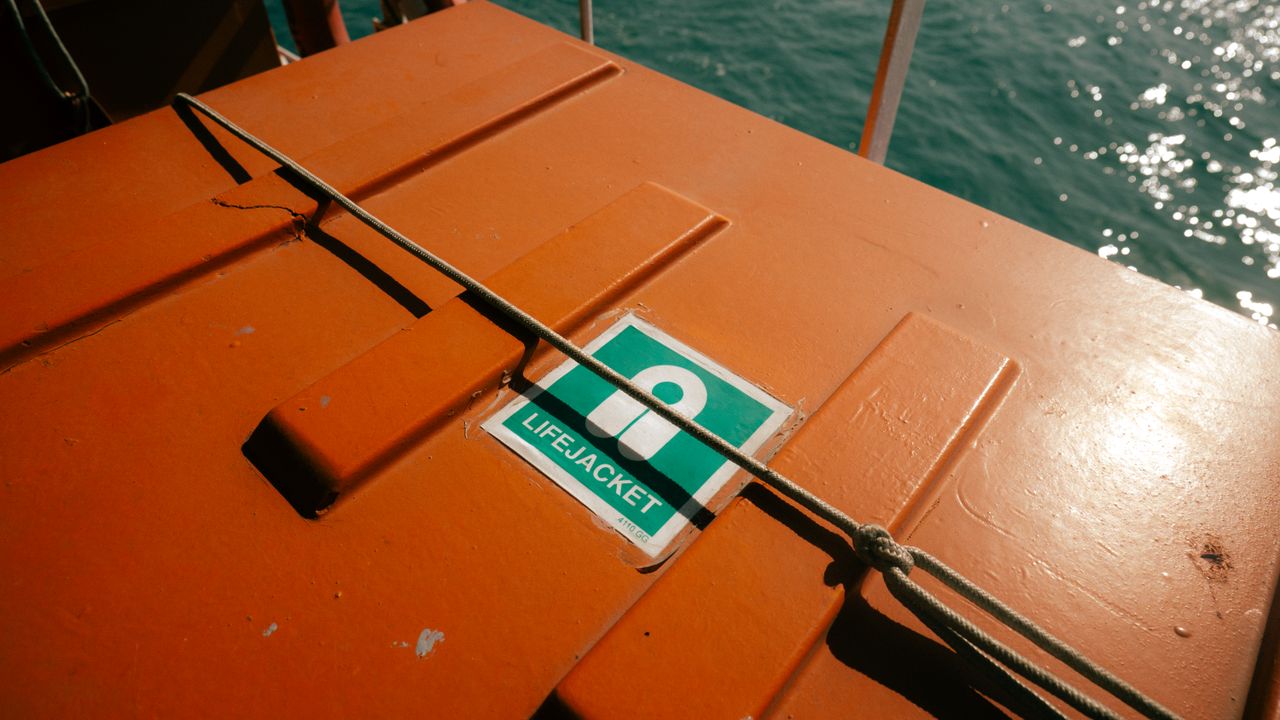 Orange emergency equipment case with a green safety sign on a boat deck