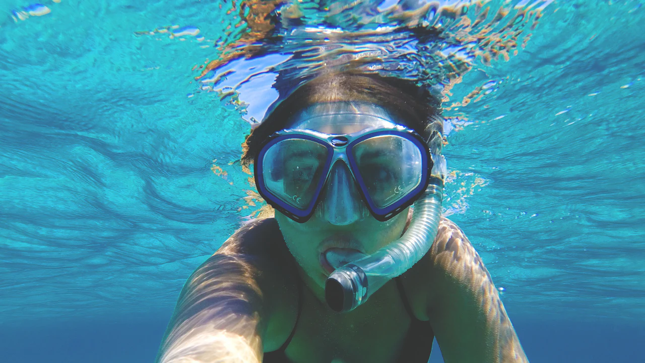 Snorkeler wearing a two-window mask and snorkel just below the surface