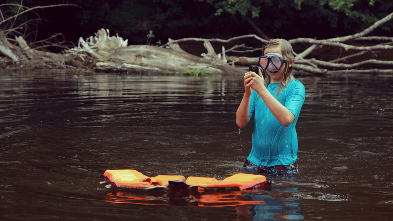 Snorkeler standing in shallow water adjusting a mask