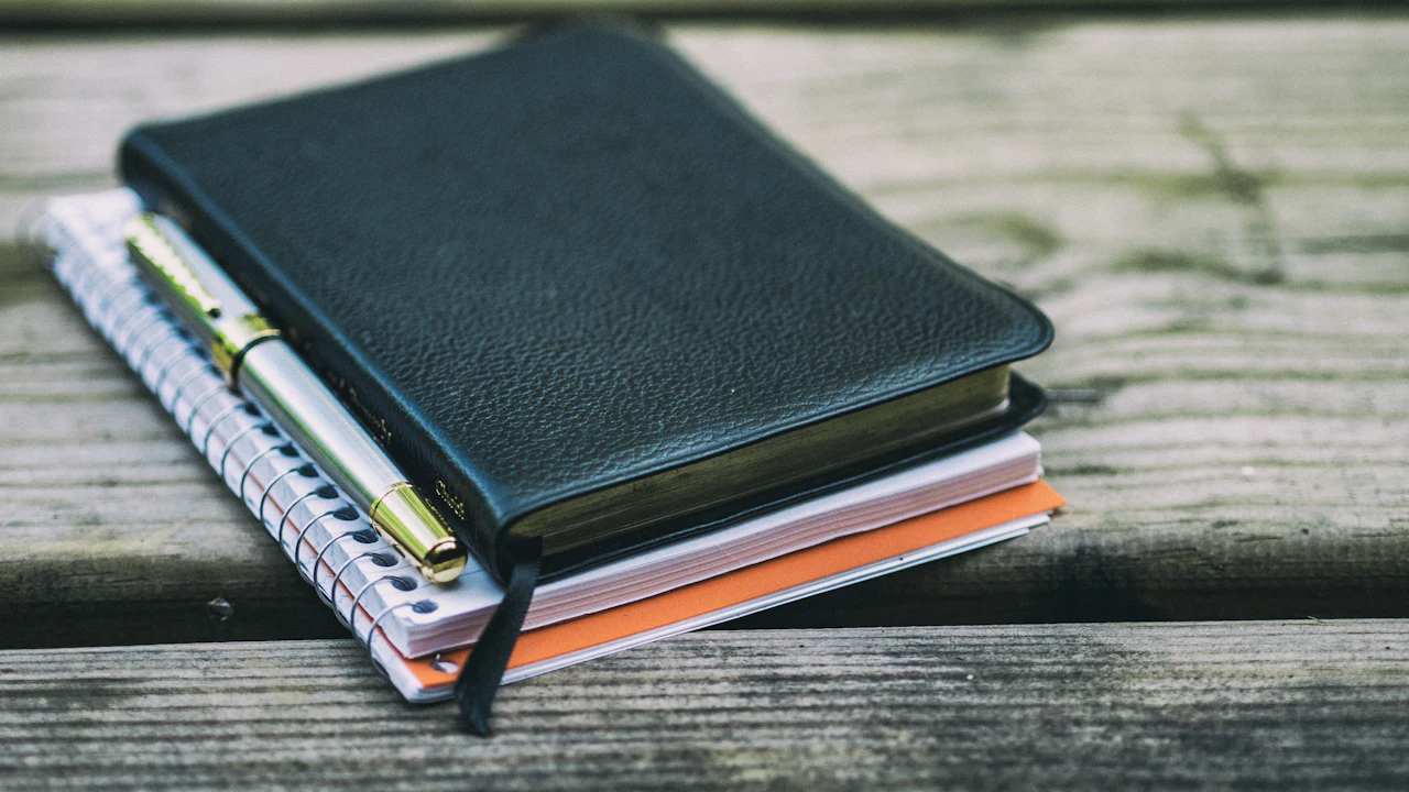Notebooks and a pen on a wooden table