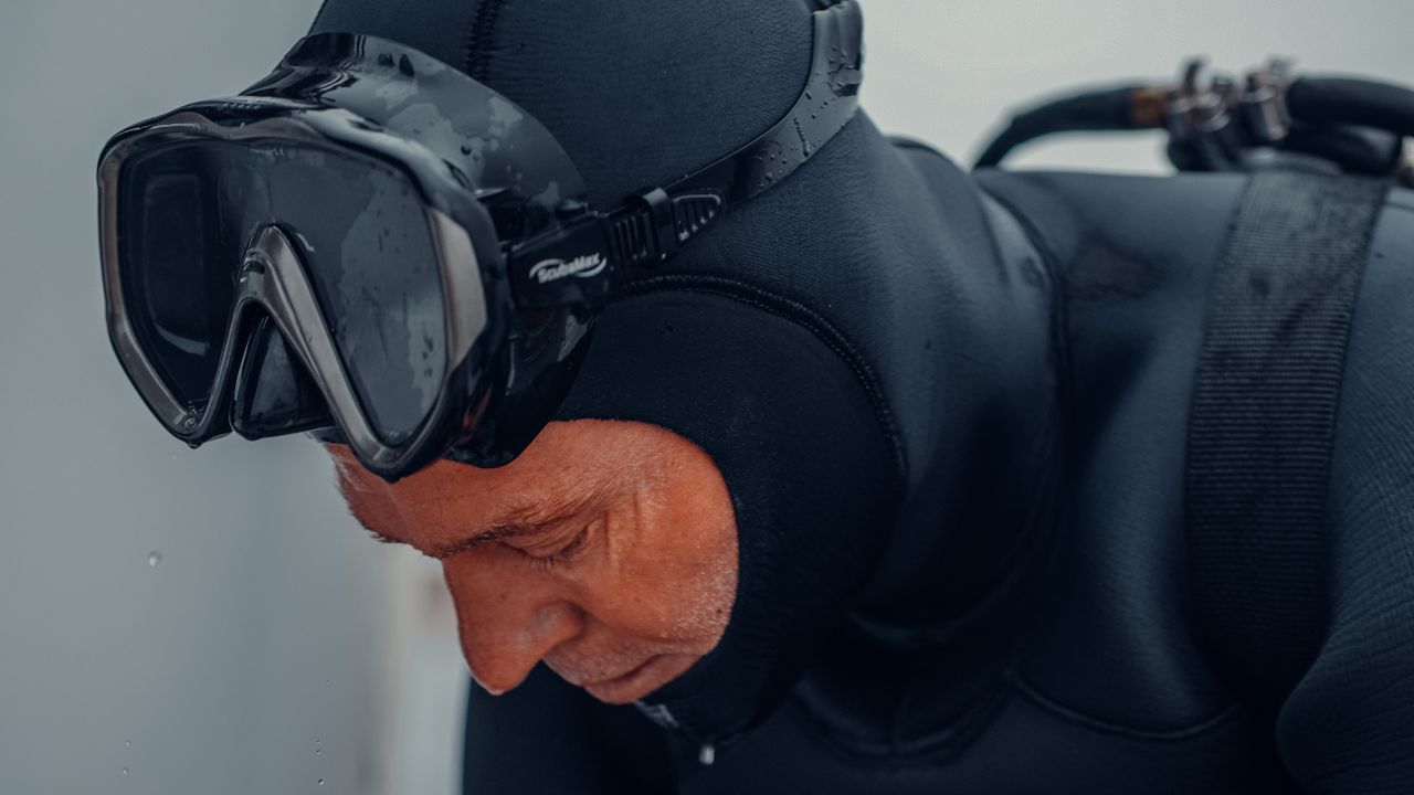 Diver in a hood and mask getting ready to dive