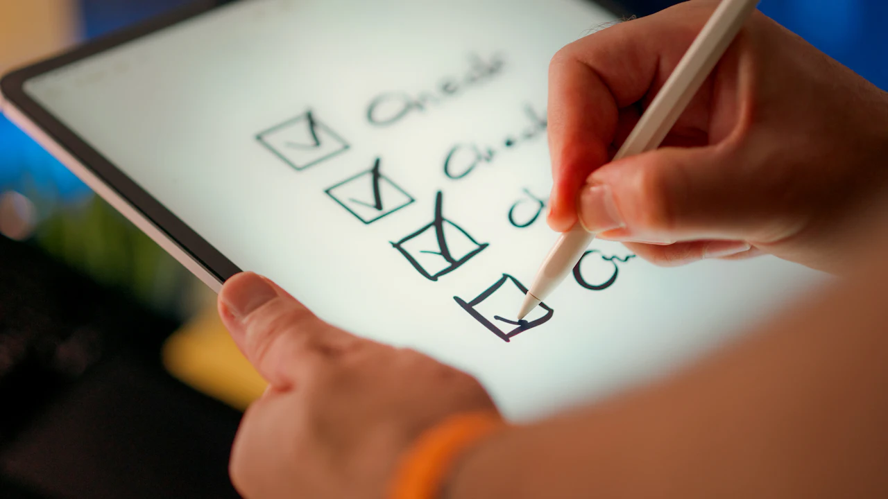 Hand ticking a checklist on a tablet screen with a stylus