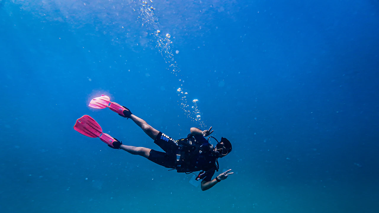 Diver with pink fins swimming in blue water