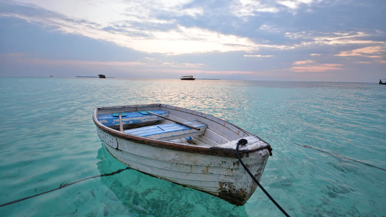 Small rowboat moored on calm turquoise water at sunrise