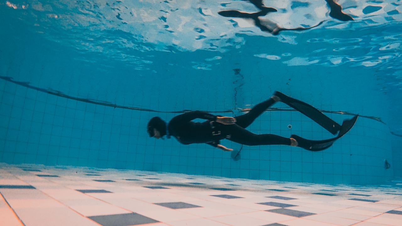 Freediver swimming along the bottom of a pool