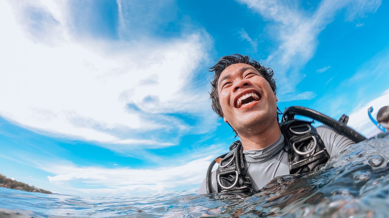 Beginner diver in a mask floating at the surface and smiling before a dive