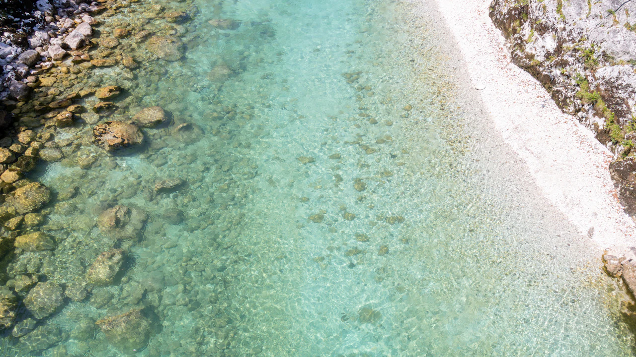 Aerial view of clear shallow water along a rocky shoreline
