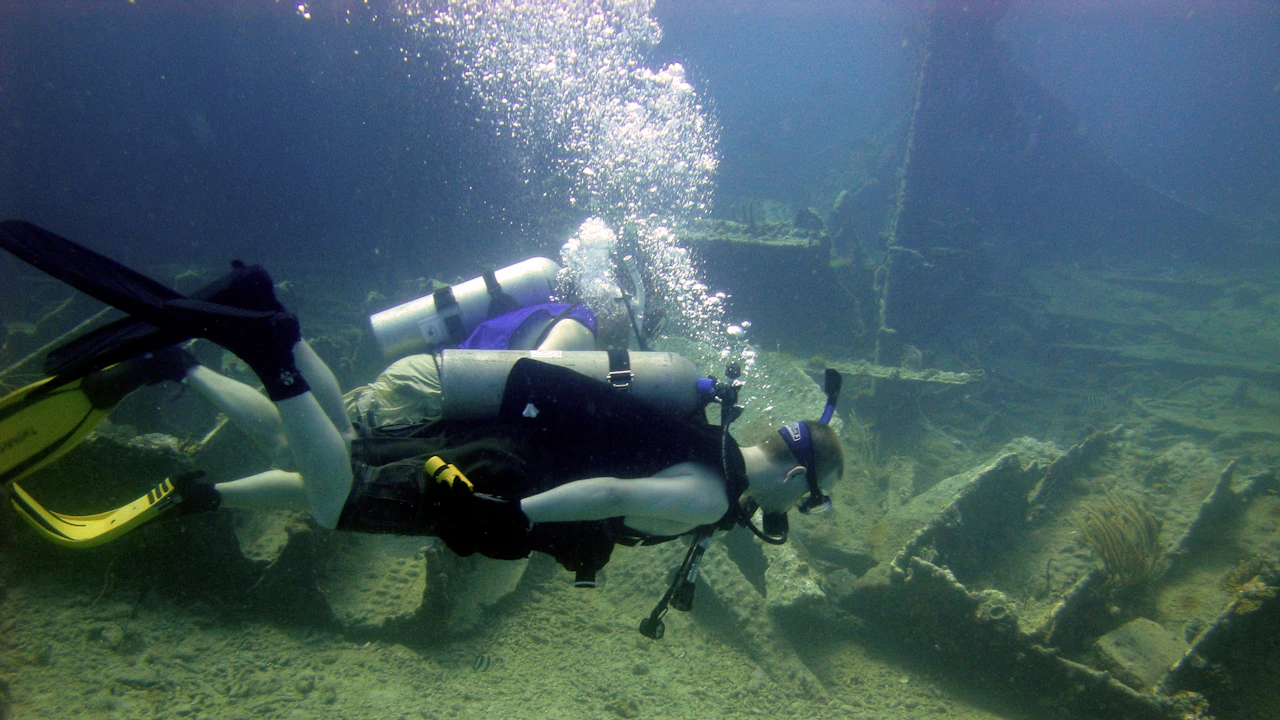 Scuba diver swimming over a shipwreck with bubbles rising