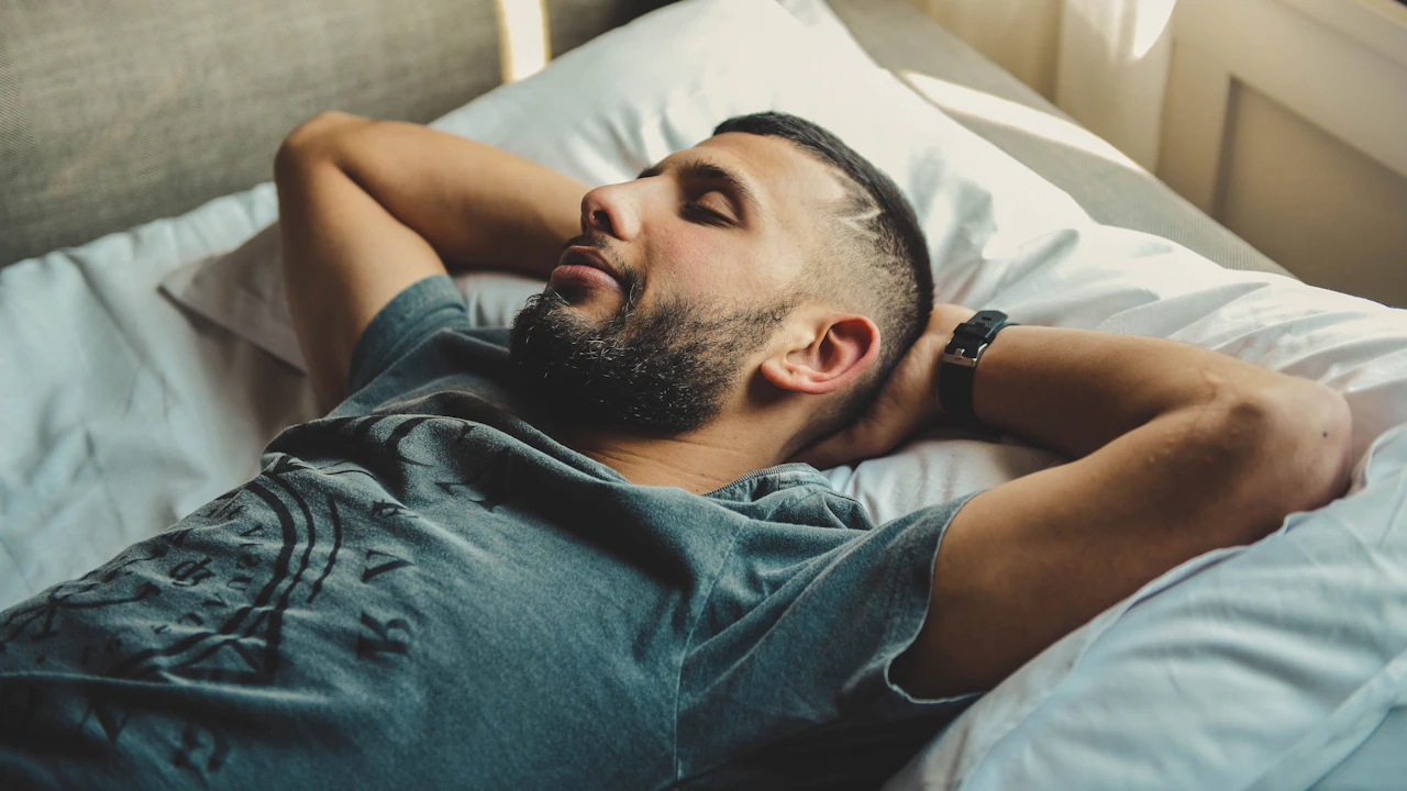 Tired man lying on a bed with his hands behind his head