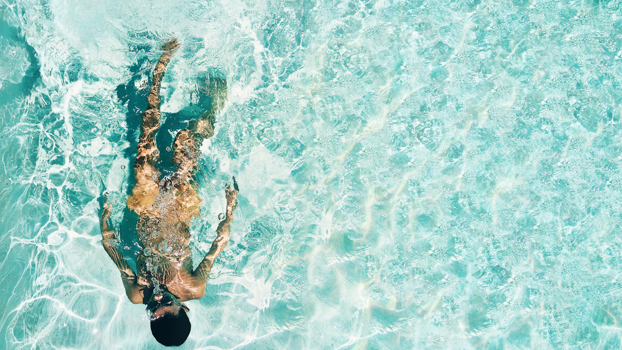 Swimmer in a clear outdoor pool seen from above