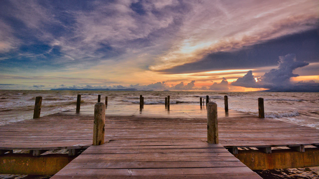 Wooden dock leading out over calm water at sunrise