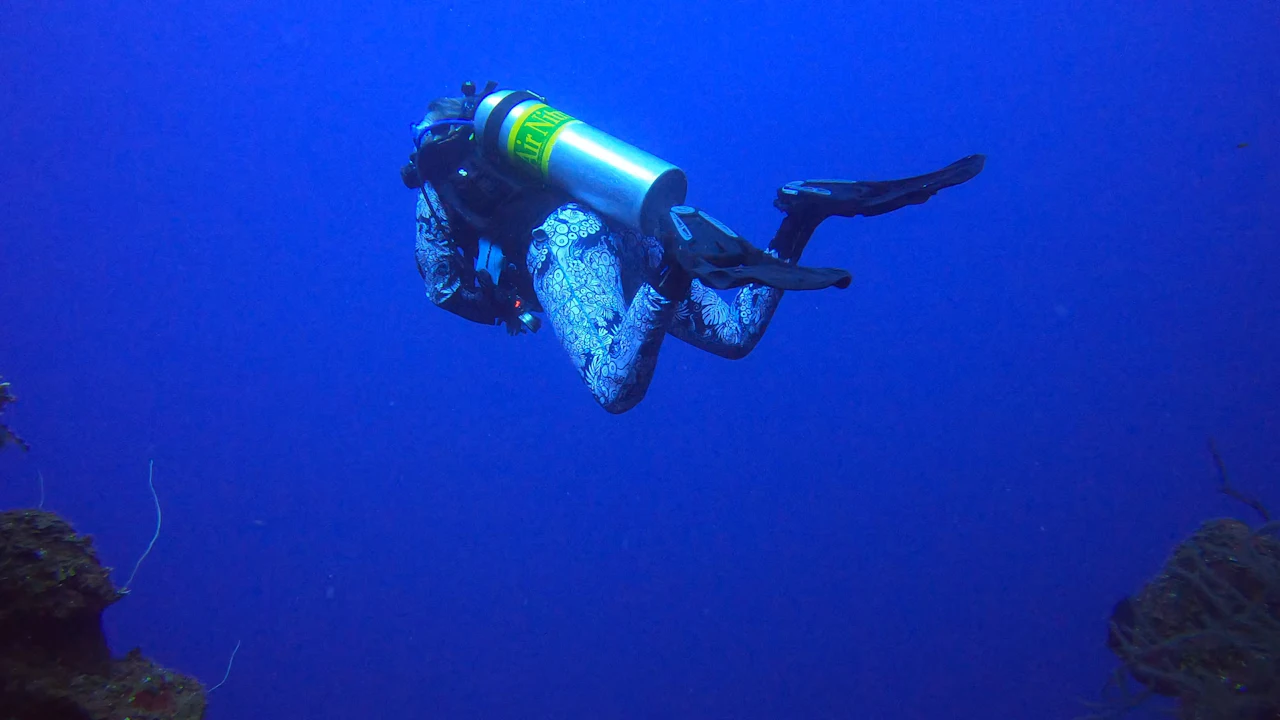 Scuba diver descending headfirst into deep blue open water
