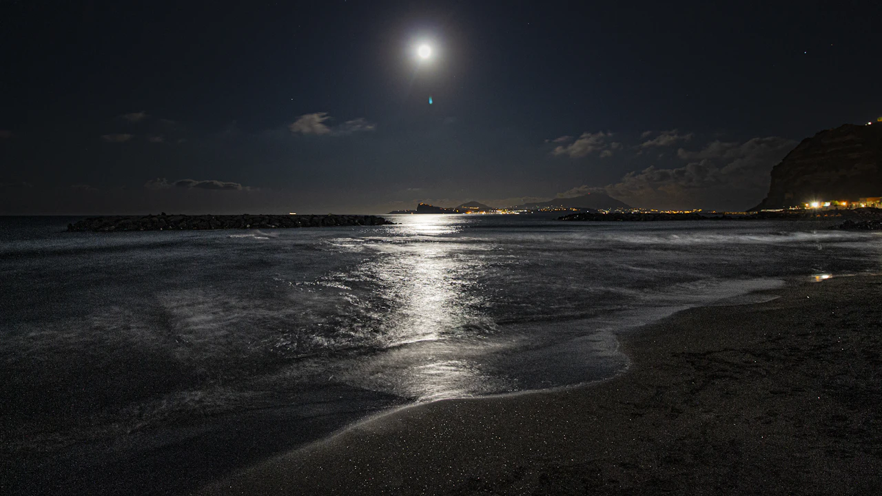 Full moon rising over a calm ocean at dusk with light on the water