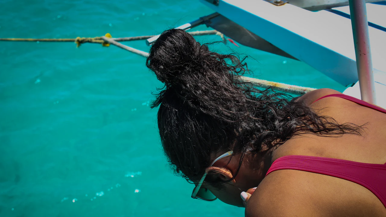 Woman leaning over the side of a boat looking at the water
