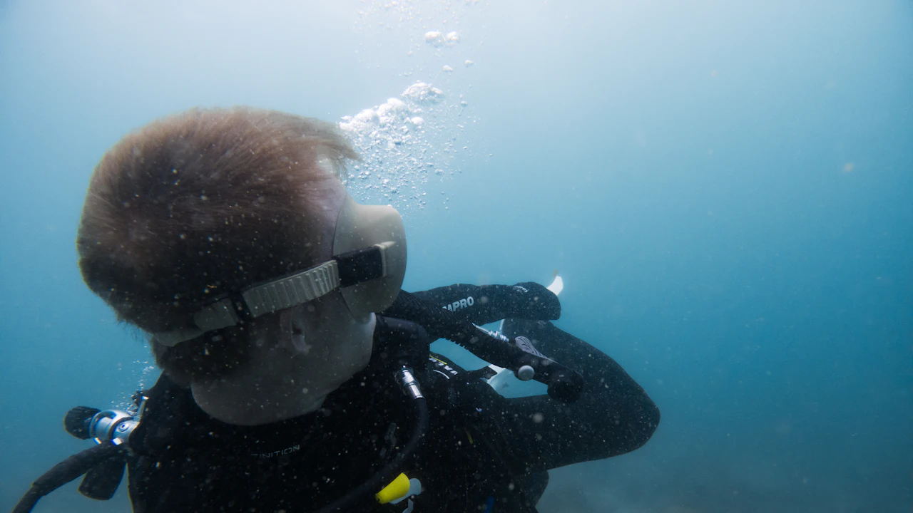 Young scuba diver wearing a mask underwater with bubbles rising