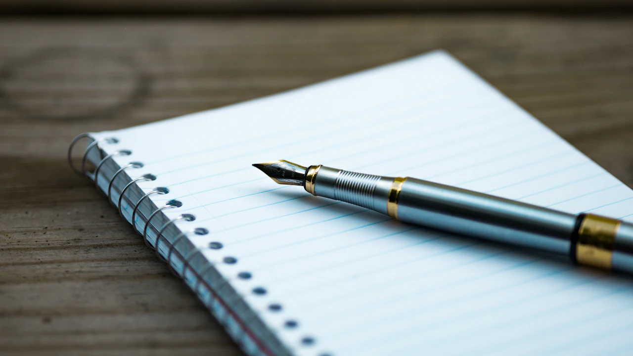 Fountain pen resting on an open spiral notebook