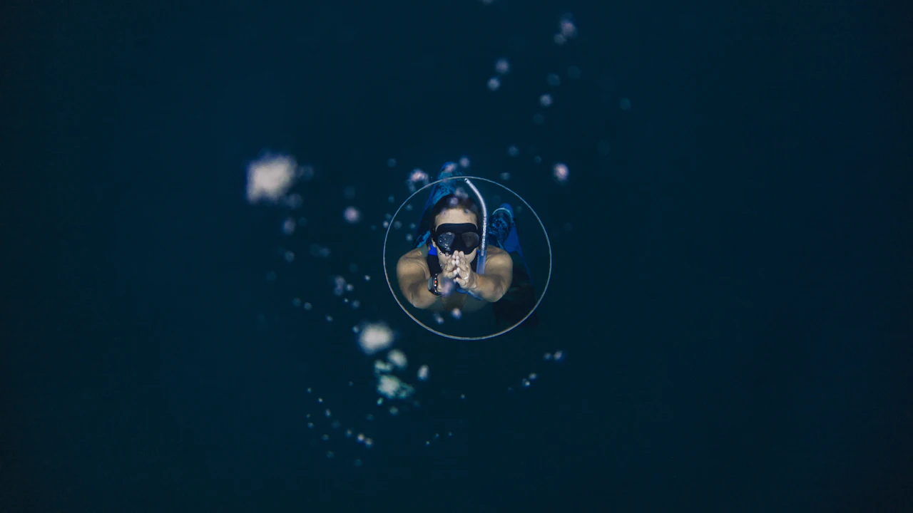 Scuba diver in a mask surrounded by bubbles in dark water