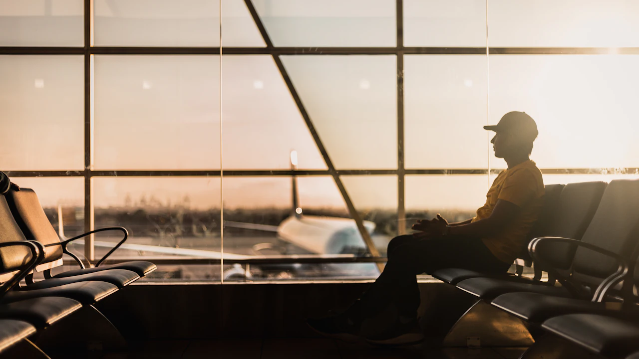 Traveler in a cap sitting by an airport window